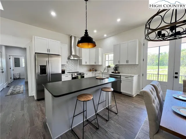 a kitchen with stainless steel appliances granite countertop a sink a stove a refrigerator cabinets a dining table and chairs