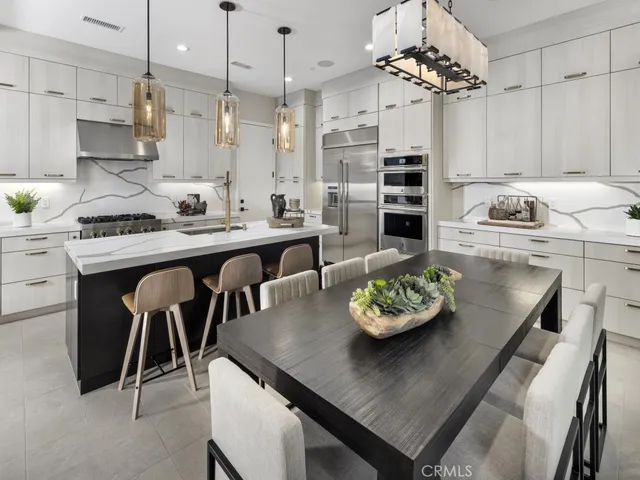 a kitchen with stainless steel appliances granite countertop a sink dishwasher a stove a refrigerator a dining table and chairs with wooden floor