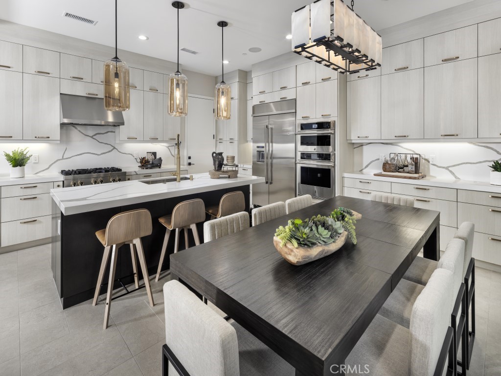 25 Remy Lane Montebello, CA 90640 - Photo 9 of 49 a kitchen with stainless steel appliances granite countertop a sink dishwasher a stove a refrigerator a dining table and chairs with wooden floor