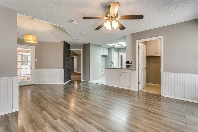 a view of an empty room with window and wooden floor