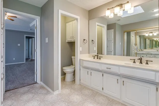 a spacious bathroom with a granite countertop sink a toilet and a mirror