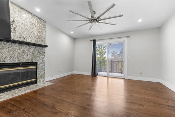 an empty room with wooden floor fireplace and windows