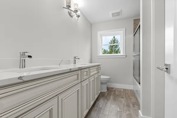 a bathroom with a double vanity sink toilet and shower