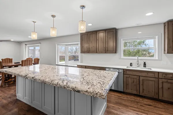 a kitchen with kitchen island granite countertop a sink stove and refrigerator