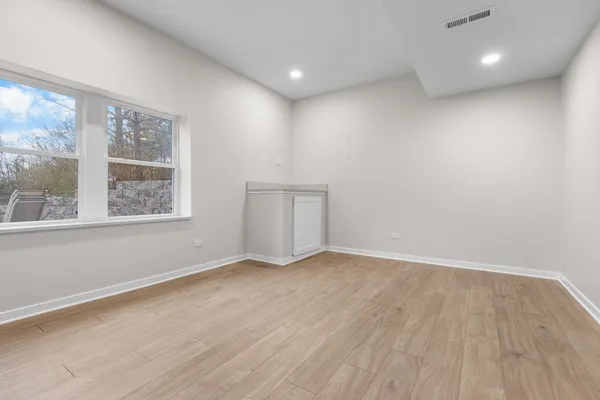 an empty room with wooden floor and windows