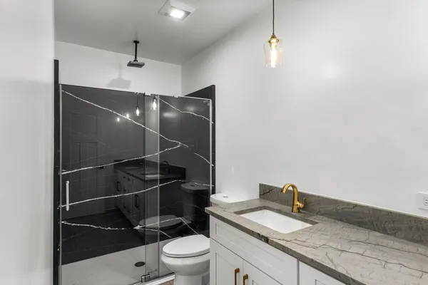 a bathroom with a granite countertop sink toilet and shower