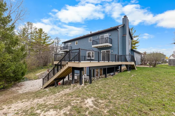 a view of a house with a wooden deck and a trees