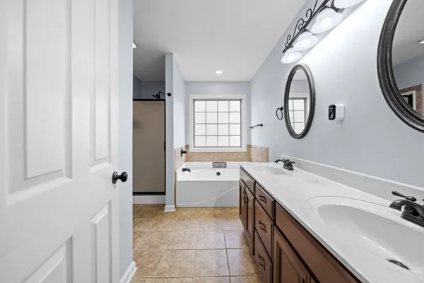 a bathroom with a double vanity sink mirror and bathtub