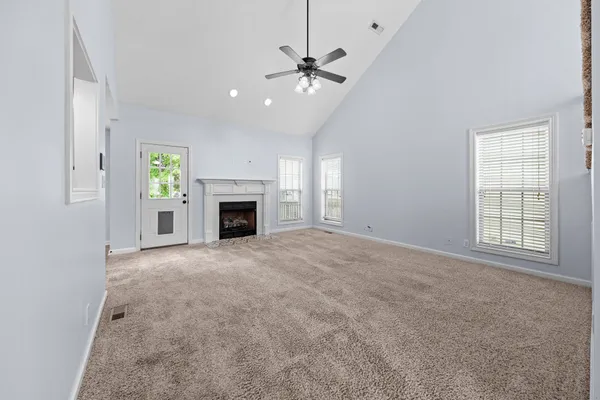 an empty room with windows and fireplace