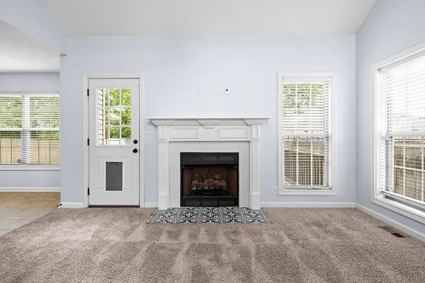 a view of an empty room with a window and fireplace
