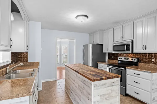 a kitchen with stainless steel appliances granite countertop a stove top oven a sink and a refrigerator