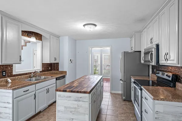 a large kitchen with stainless steel appliances granite countertop a sink stove and refrigerator