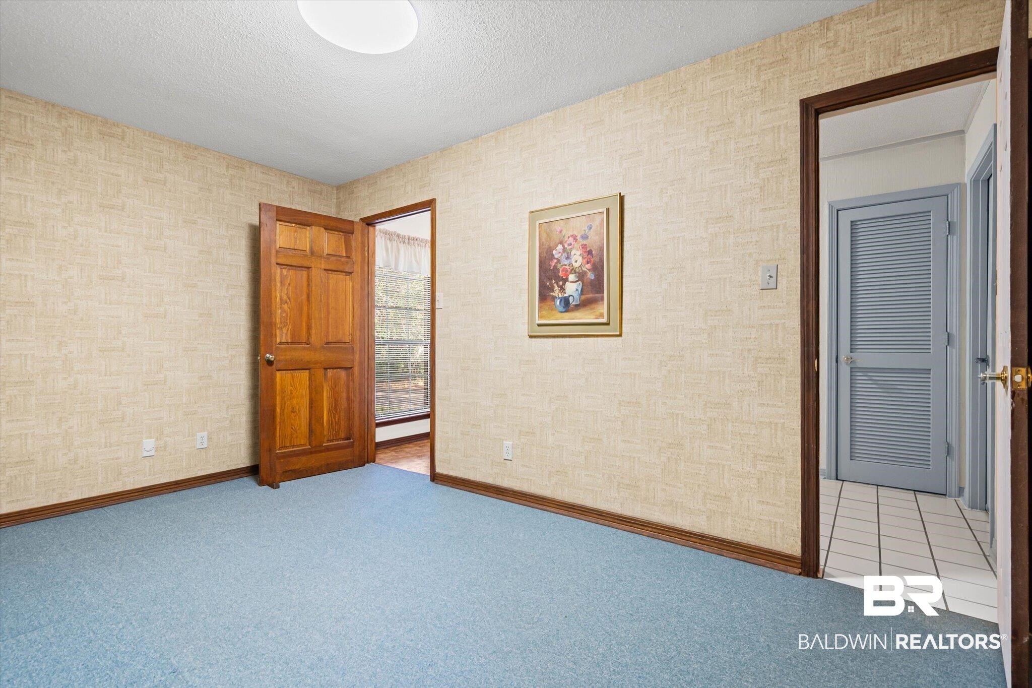 1900 Foxfire Road Mobile, AL 36618 - Photo 16 of 36 Carpeted empty room with a textured ceiling, tile patterned floors, and wallpapered walls