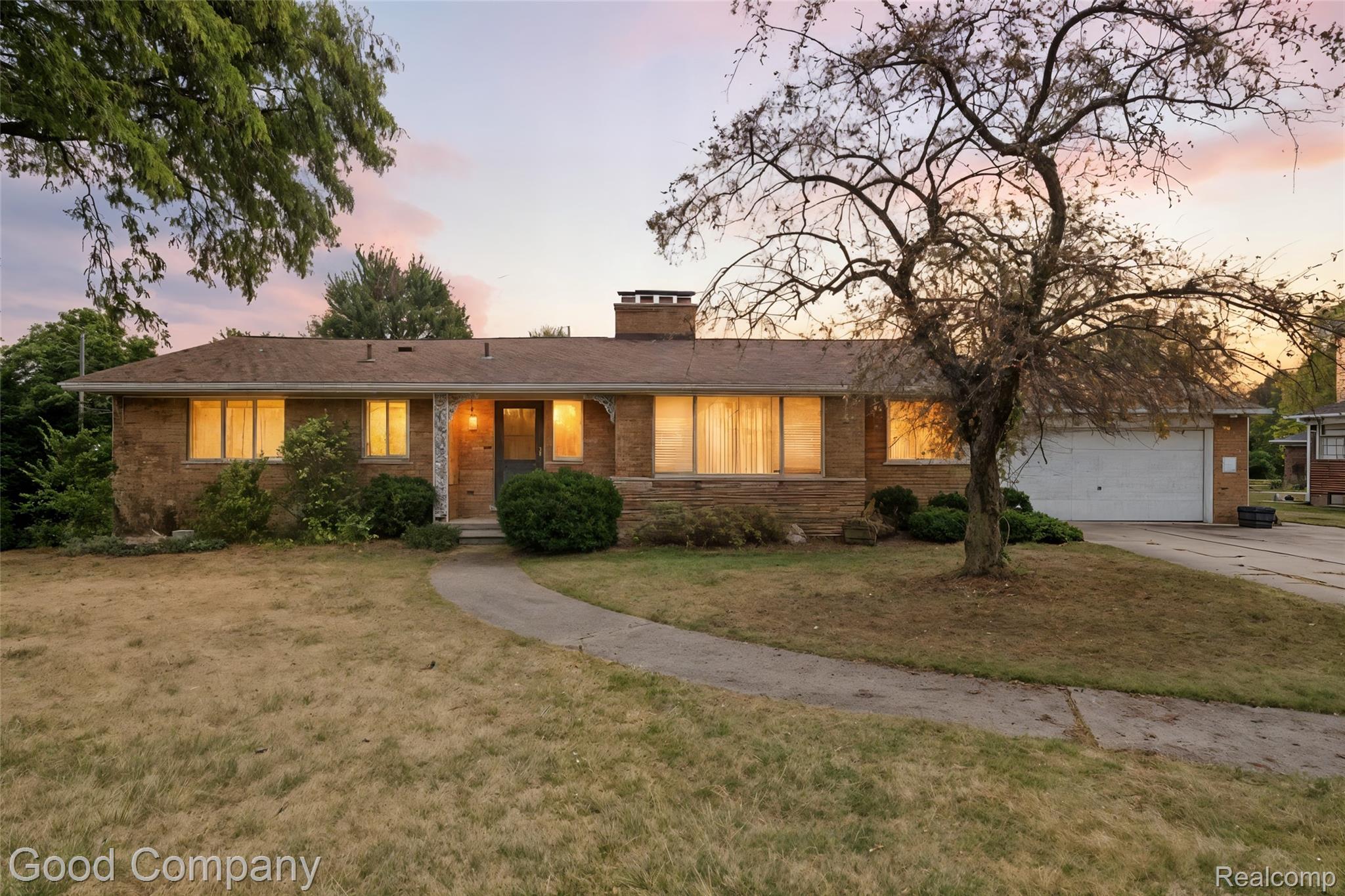 Single story home with concrete driveway, a chimney, a front lawn, brick siding, and an attached garage