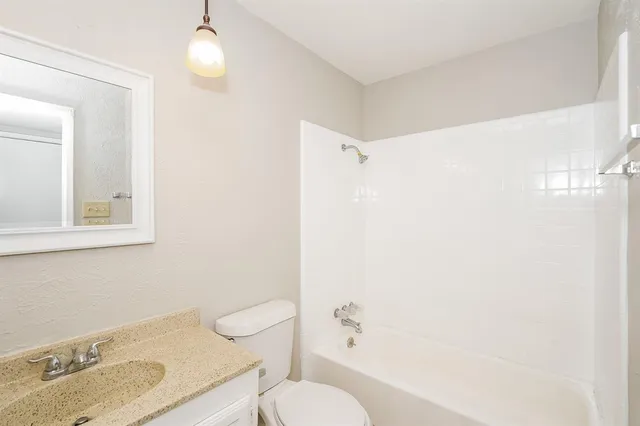 a bathroom with a granite countertop sink toilet and shower