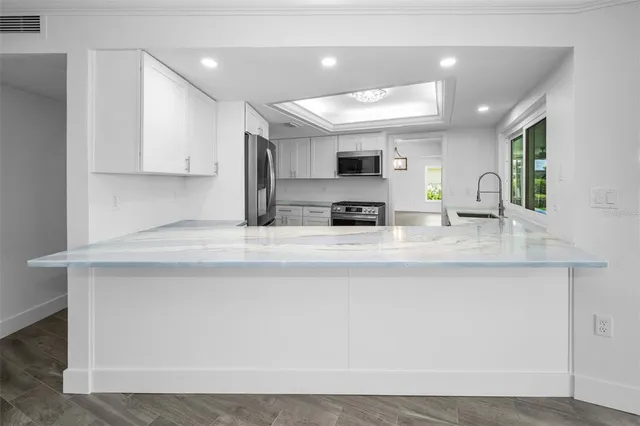 a kitchen with kitchen island granite countertop a sink a counter top space stainless steel appliances and cabinets