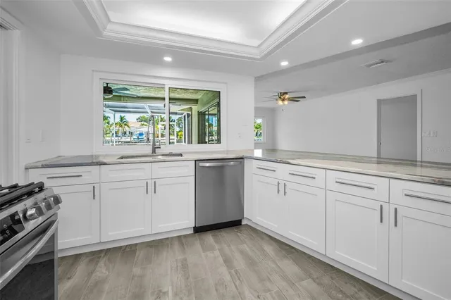 a kitchen with white cabinets appliances a sink and a window
