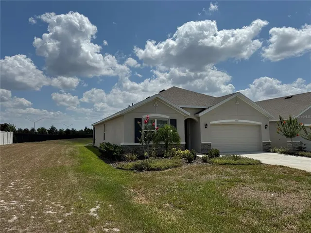 a front view of house with yard and trees in the background