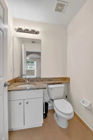 a bathroom with a granite countertop toilet sink and mirror