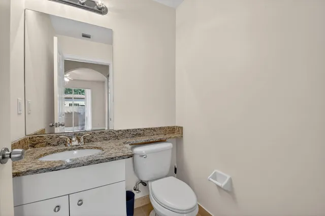 a bathroom with a granite countertop toilet sink and mirror