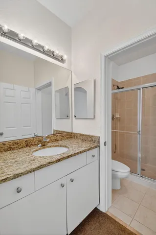 a bathroom with a granite countertop sink a toilet a mirror and shower