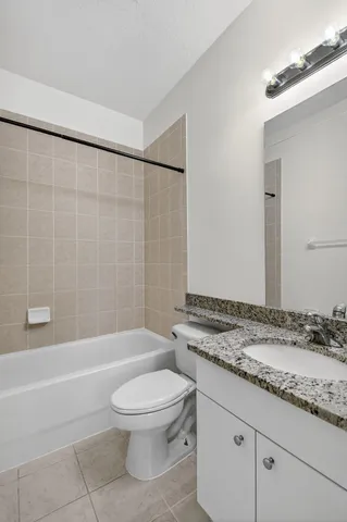 a bathroom with a granite countertop toilet a sink and a bathtub