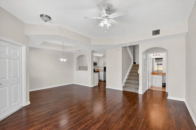 a view of an empty room with wooden floor and stairs