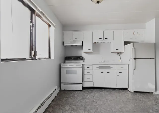 a kitchen with white cabinets and white appliances