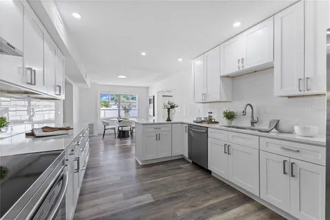 a kitchen with white cabinets sink and stove