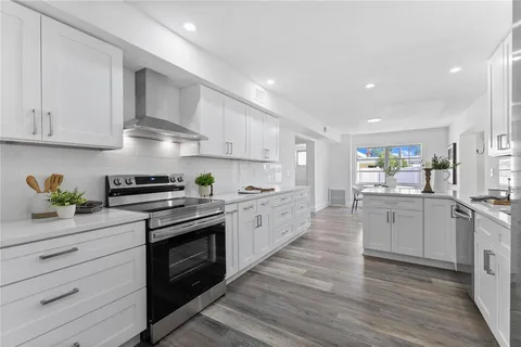 a large kitchen with cabinets wooden floor and stainless steel appliances