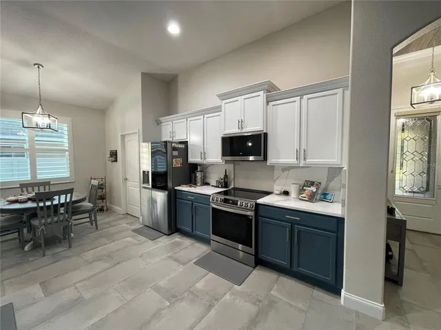 a kitchen with stainless steel appliances granite countertop a stove top oven a sink dishwasher a dining table and chairs with wooden floor