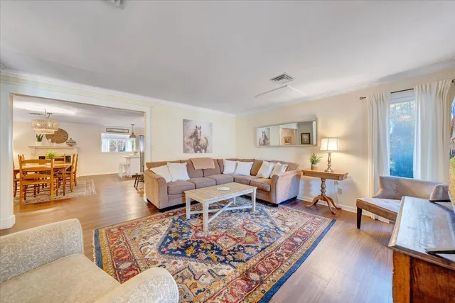 a living room with furniture a dining table and large windows with wooden floor