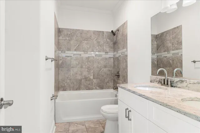 a bathroom with a granite countertop bathtub shower sink vanity and toilet