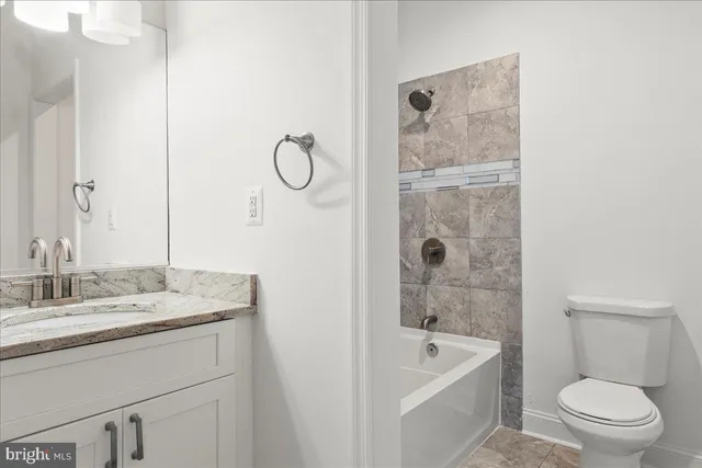 a bathroom with a granite countertop sink a toilet and shower