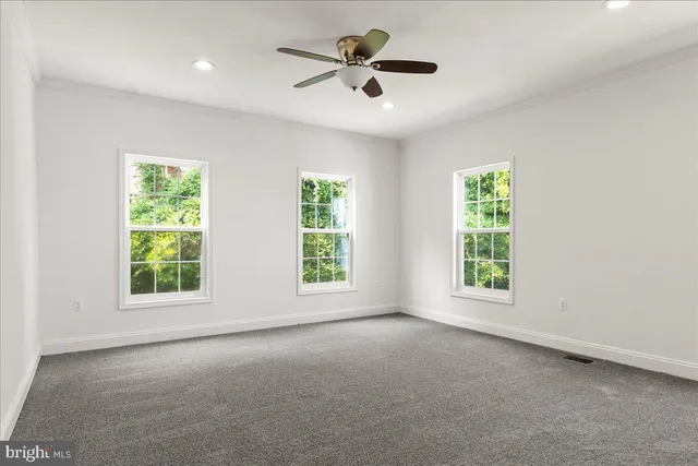an empty room with windows and a ceiling fan