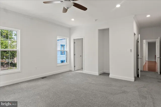 an empty room with ceiling fan and windows