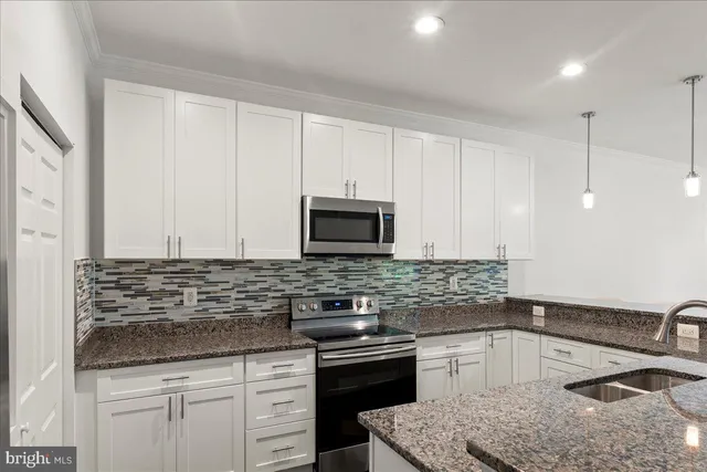 a kitchen with granite countertop a sink a stove and cabinets