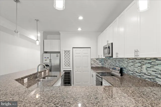 a kitchen with stainless steel appliances kitchen island granite countertop a sink and a refrigerator