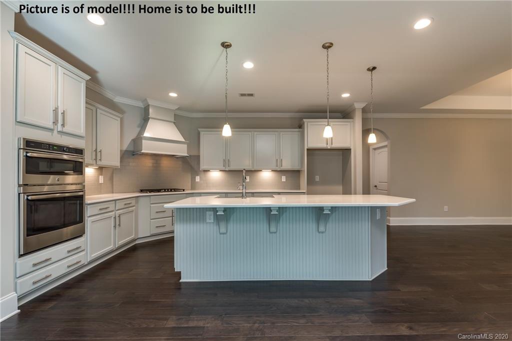 2061 New Style Way, Unit 30 Tega Cay, SC 29708 - Photo 24 of 40 a large kitchen with stainless steel appliances a large counter top a stove a sink cabinets and a wooden floor
