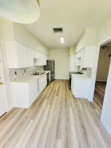 a large kitchen with a sink dishwasher white cabinets and stainless steel appliances
