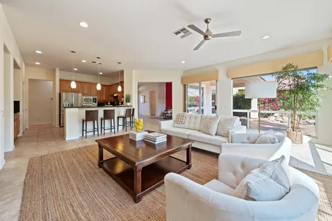 a living room with furniture kitchen view and a wooden floor