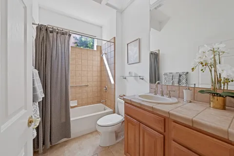 a bathroom with a granite countertop sink a toilet a mirror and shower