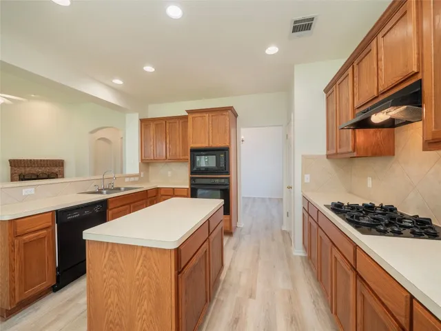a kitchen with granite countertop a stove top oven sink and cabinets