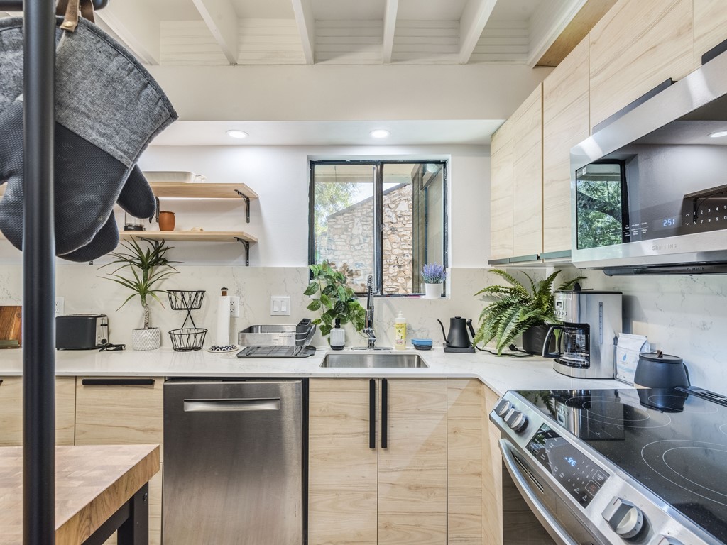500 East Riverside Drive, Unit 206 Austin, TX 78704 - Photo 9 of 32 Kitchen with light wood finish cabinetry, stainless steel appliances, modern cabinets, and beam ceiling