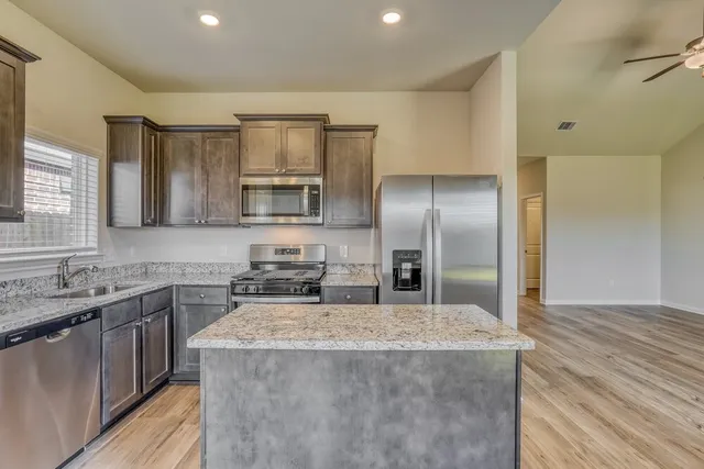 a kitchen with kitchen island granite countertop a sink stove and refrigerator