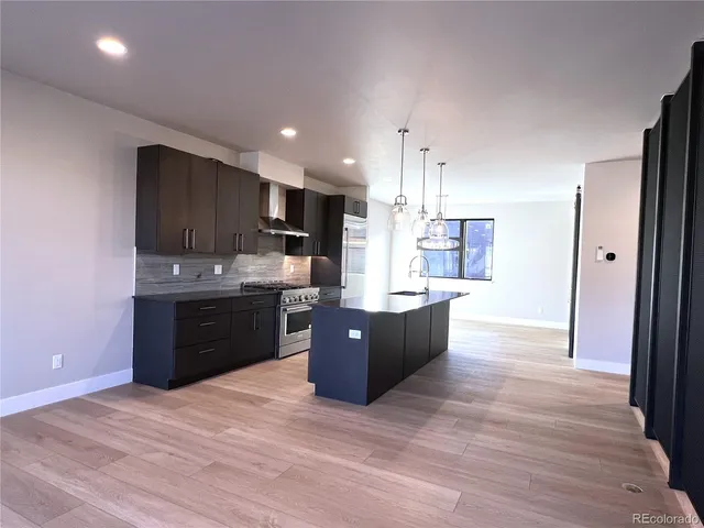 a large kitchen with stainless steel appliances kitchen island granite countertop a stove a refrigerator a sink dishwasher and a oven with wooden floor