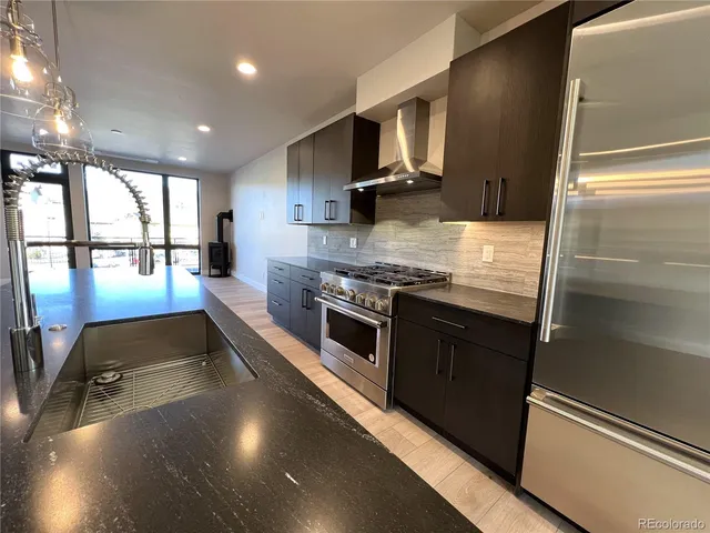 a kitchen with stainless steel appliances granite countertop a stove a sink and a refrigerator