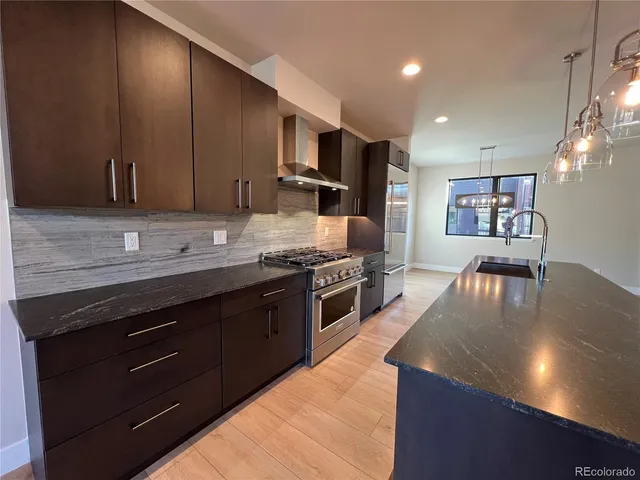 a kitchen with stainless steel appliances granite countertop a stove a sink and a microwave