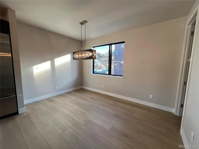 an empty room with wooden floor cabinet and windows