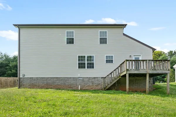 a view of backyard of house along with deck and outdoor seating